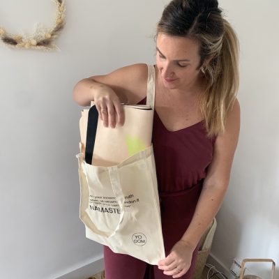 Jeune femme qui met son tapis de yoga de voyage Yogom dans un totebag