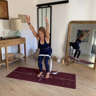 Tapis de yoga Performance Yogom Samadhi raisin bodyline avec Caroline en posture de la chaise aidée d'une sangle au niveau des cuisses